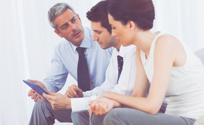 Business people talking about files on sofa at office